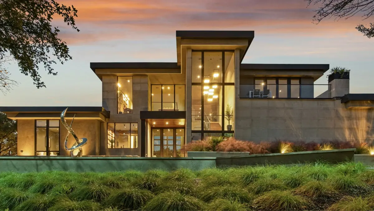 A modern luxury home at dusk with glowing floor-to-ceiling windows