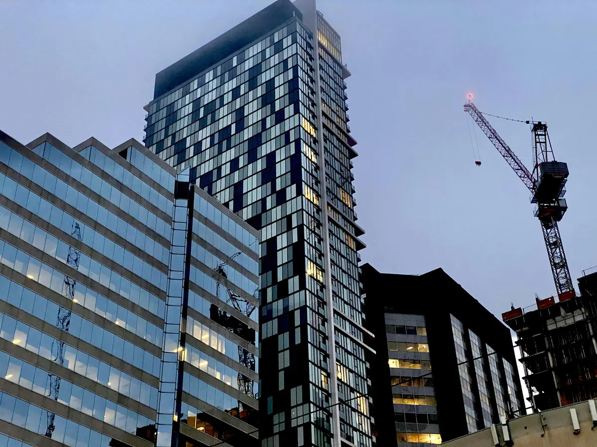 Toronto condominium towers rising beside a construction crane at dusk